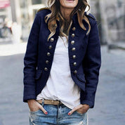 Giacca militare donna blu scuro con bottoni dorati, abbinata a t-shirt bianca e jeans strappati. Stile casual chic, moda autunnale.