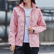 Giacca a vento rosa con motivo floreale, indossata da una donna. Ideale per attività all'aperto, moda casual, abbigliamento primaverile.