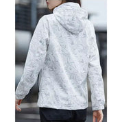 Giacca a vento bianca con cappuccio, motivo foglie, donna di spalle. Abbigliamento outdoor, impermeabile, stile casual, moda autunnale.