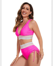 Donna sorridente in bikini rosa acceso con dettagli in pizzo bianco, posa su sfondo bianco. Moda mare, costumi da bagno estivi, abbigliamento da spiaggia.