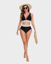 Donna in costume da bagno nero a due pezzi con dettagli bianchi, cappello di paglia, occhiali da sole e borsa intrecciata. Moda estiva mare.