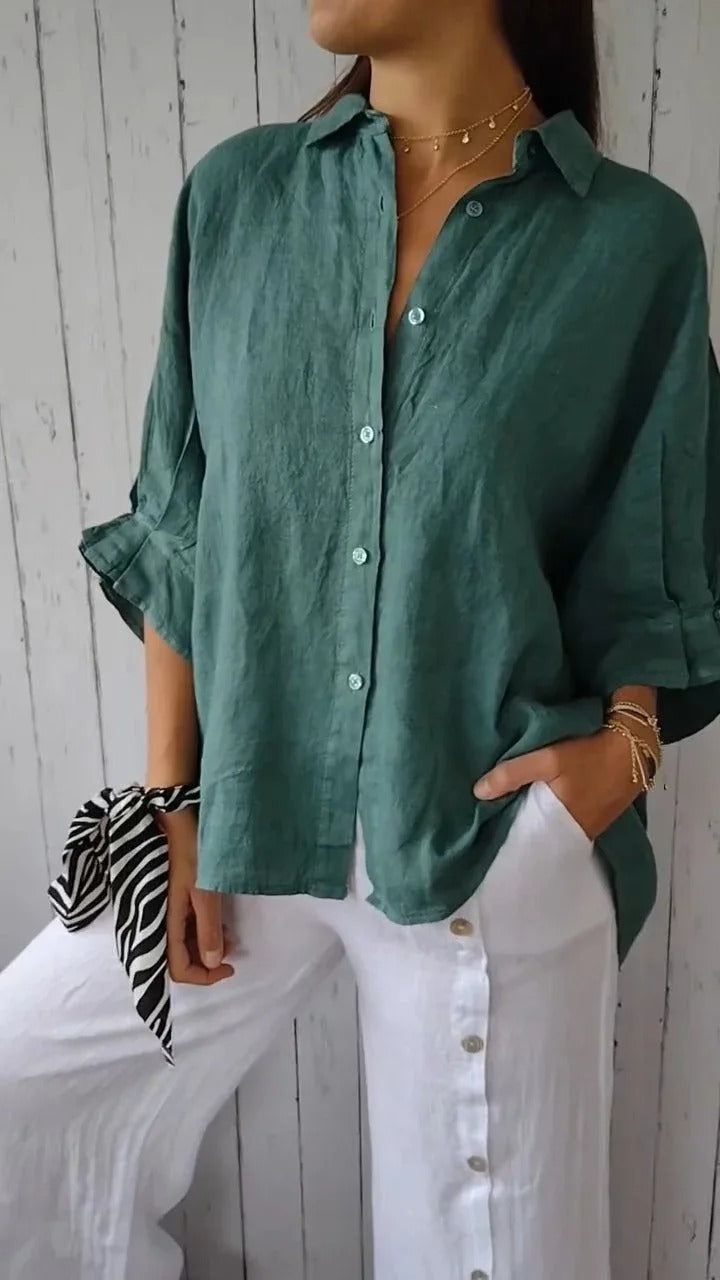 Camicia verde in lino da donna, maniche lunghe, abbinata a pantaloni bianchi con bottoni. Look casual ed elegante, moda estiva.