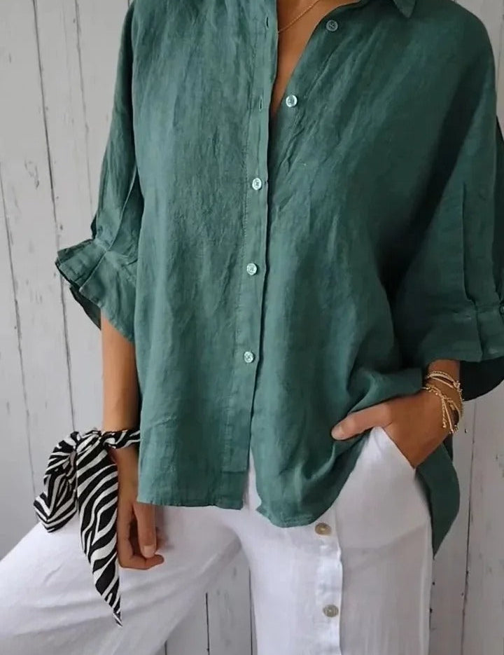 Camicia verde in lino da donna, maniche lunghe, abbinata a pantaloni bianchi con bottoni. Look casual ed elegante, moda estiva.