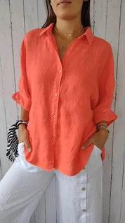 Camicia donna in lino arancione, maniche lunghe, abbinata a pantaloni bianchi. Moda estiva casual, stile elegante e fresco.