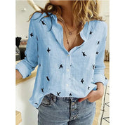 Camicia donna azzurra con stampa uccelli neri, maniche lunghe, abbinata a jeans. Moda casual, stile primaverile, abbigliamento femminile trendy.