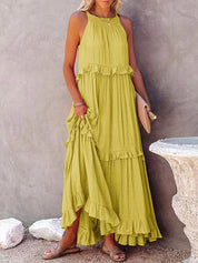 Abito lungo estivo verde lime con balze, senza maniche, indossato da una donna. Perfetto per look casual e vacanze. Accessoriato con sandali e pochette.