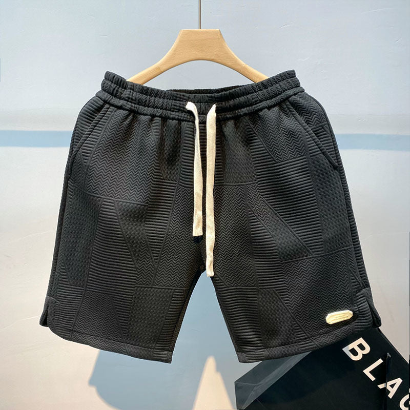 Pantaloncini sportivi neri da uomo con motivo geometrico, elastico in vita e laccio bianco. Ideali per allenamento e tempo libero.