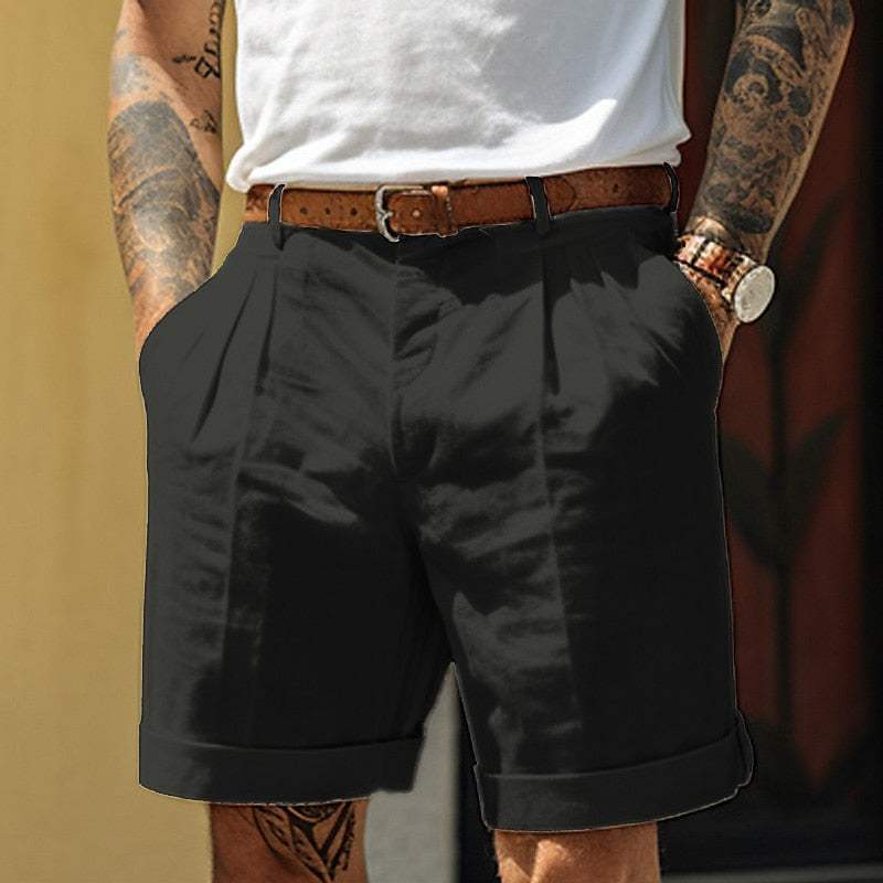 Uomo con pantaloncini neri eleganti, cintura marrone, camicia bianca. Moda estiva maschile, look casual chic, tendenze abbigliamento uomo.
