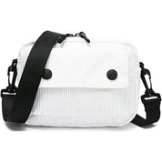 Borsa a tracolla bianca in tessuto a coste, con patta frontale e bottoni neri, tracolla regolabile nera. Accessorio moda casual e versatile.