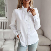 Camicia bianca da donna con colletto arricciato, maniche lunghe, abbinata a jeans chiari. Look casual ed elegante per moda femminile.