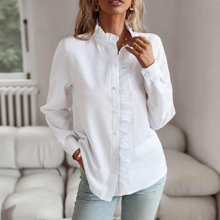 Camicia bianca da donna con colletto arricciato, maniche lunghe, abbinata a jeans chiari. Look casual ed elegante per moda femminile.